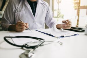 A medical professional sitting at a desk looking through documents